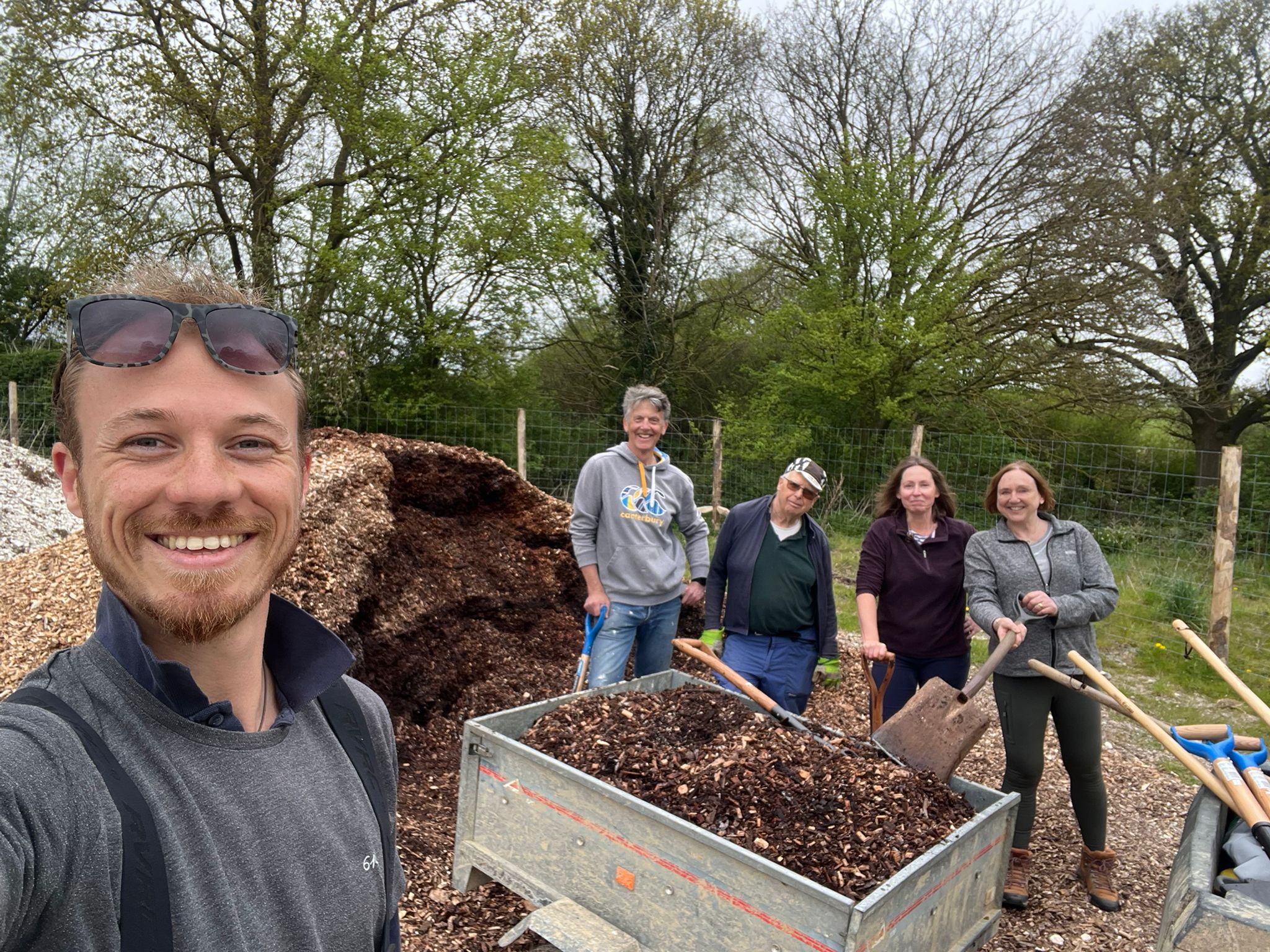 Selfie taken by task leader with volunteers and a trailer of woodchip behind